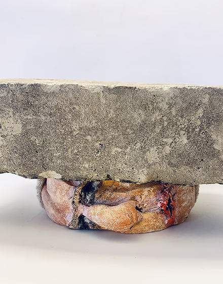 Soft sculpture head crushed by a brick