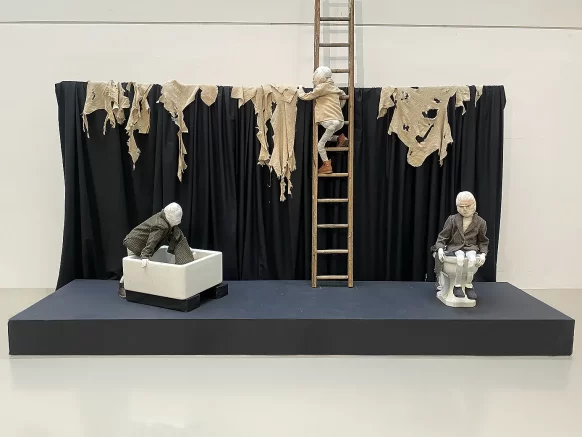 Installation view of a stage with 3 boys sculptures.