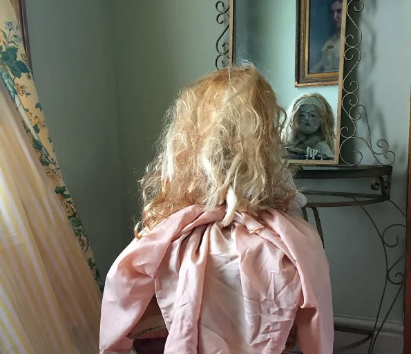 Room corner with girl sculpture looking into mirror and holding a hair brush