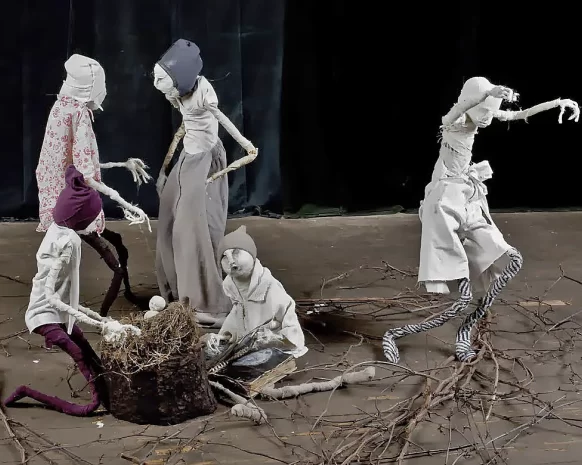 Five boy sculptures on a stage either chatting, reading or dancing. A basket with straw and an infant in the center