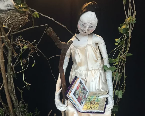 Girl sitting on branch holding an open book