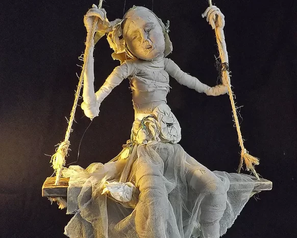 Child sculpture sitting dreamily on a swing