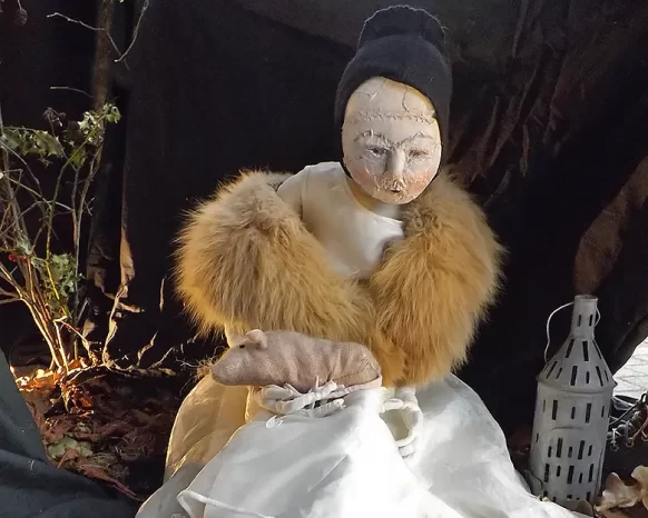 Girl sculpture in white dress and fur stole with an open book on the floor