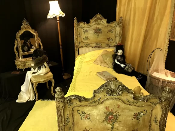 Partial view into a bedroom with dominant yellow colour design with two woman sculptures.